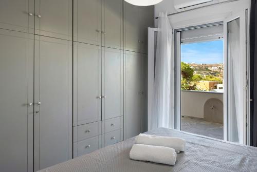 a bedroom with a bed and a large window at Sunset Realty Apartment in Ano Syros