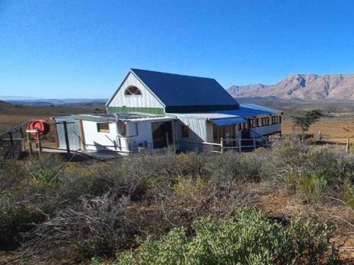 a white barn with a blue roof in a field at Botterboom - Private Karoo Campsite in Barrydale