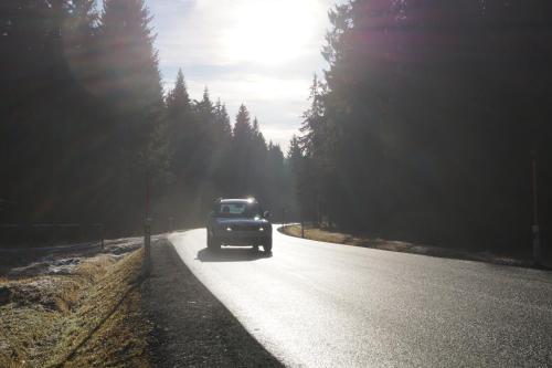 a car is driving down a road with trees at Apartments Klinovec in Loučná pod Klínovcem