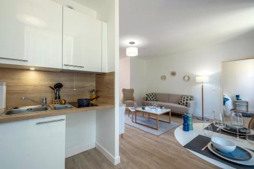 une cuisine avec des armoires blanches et un salon dans l'établissement Résidence de Poitiers, à Poitiers