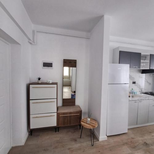 a kitchen with white cabinets and a table and a chair at Vily Apartment in Focşani
