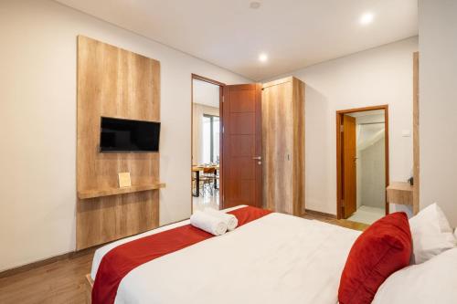 a bedroom with a bed and a tv on the wall at Cove Villa Prana in Jimbaran
