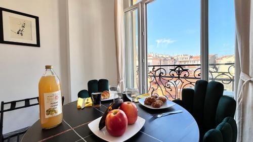 - une table à manger avec une bouteille de jus d'orange et des fruits dans l'établissement Ze Perfect Place - Studio centre-ville - Masséna, à Nice