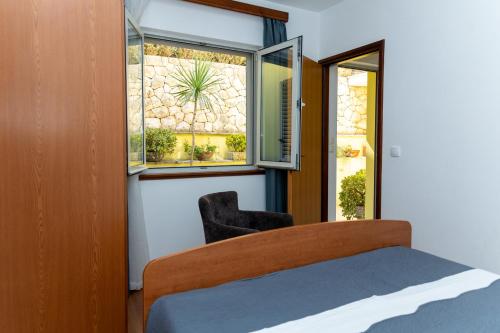a bedroom with a bed and a window and a chair at Apartments Radaic in Prigradica