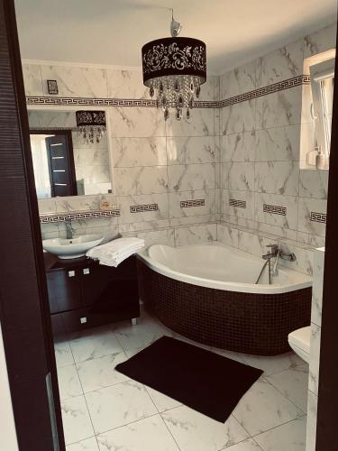a bathroom with a tub and sink and a chandelier at Dworek Kolorado dom 180 m2 na wyłączność - wyposażony in Klimki