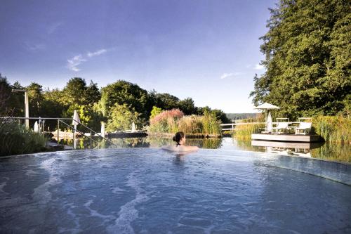 a person in a swimming pool in a lake at Heilthermen Resort Bad Waltersdorf in Bad Waltersdorf