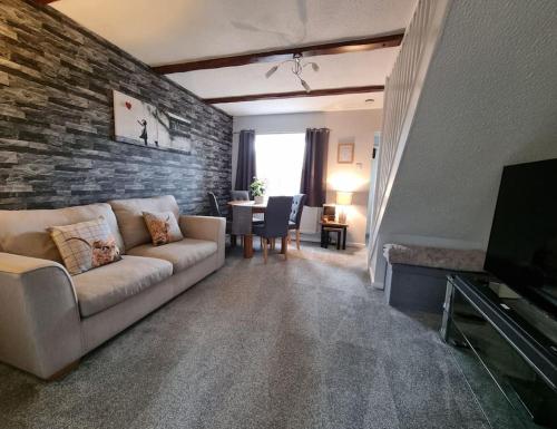 a living room with a couch and a brick wall at The Humsford Hideaway 2 bedroom home with driveway in Cramlington