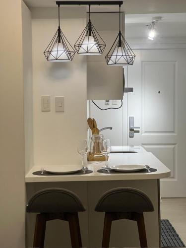 a kitchen with two bar stools and two lights at Azure North Pampanga Bachelor Pad in San Fernando