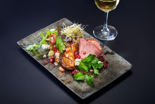 a plate of food with meat and a glass of wine at Hotel Gatsby by HappyCulture in Chassieu