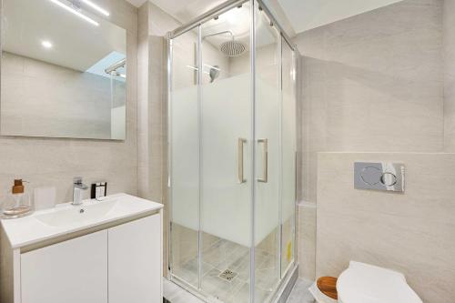 une salle de bain blanche avec une douche et un lavabo dans l'établissement Charming apartment - 1BR-5P - Opéra Garnier, à Paris