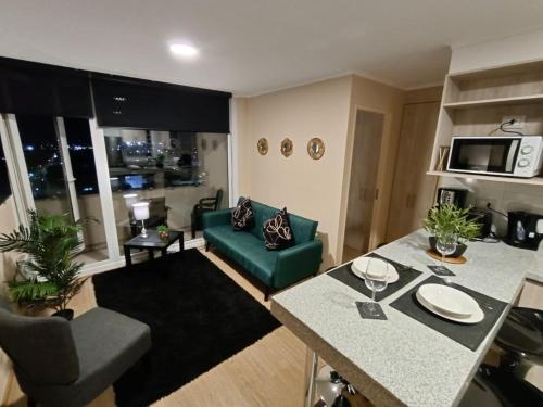 a living room with a green couch and a table at APART CENTRO CHILLAN - Departamentos Diarios in Chillán