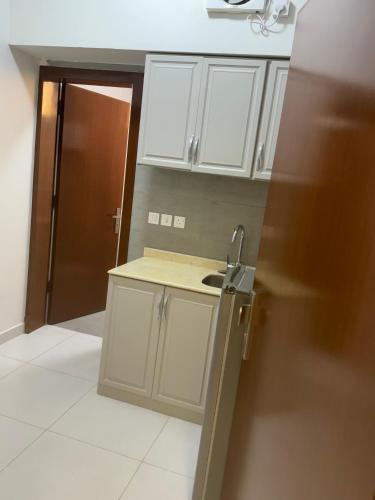 a kitchen with white cabinets and a sink at Evora إيفورا in Sharurah