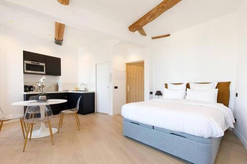 een slaapkamer met een groot bed en een tafel bij Appartement 33 m2 comme une junior suite - vue Port et Palais des festivals in Cannes