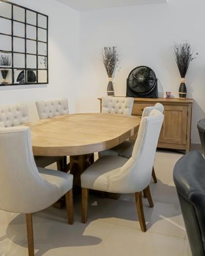a dining room with a wooden table and white chairs at 3BR villa and maid room by escape time in Sharm