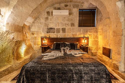 een slaapkamer met een bed in een stenen muur bij Zümrütü anka cave in Urgup