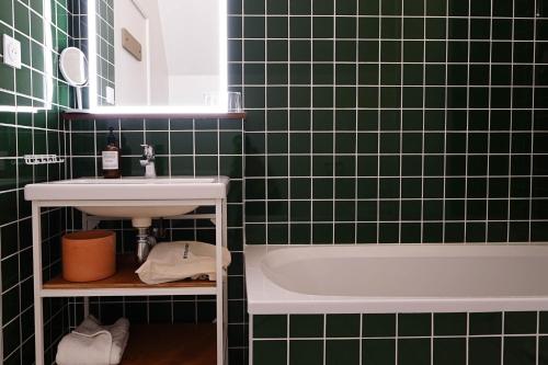 a green tiled bathroom with a sink and a bath tub at ALFRED HOTELS Compiègne in Compiègne
