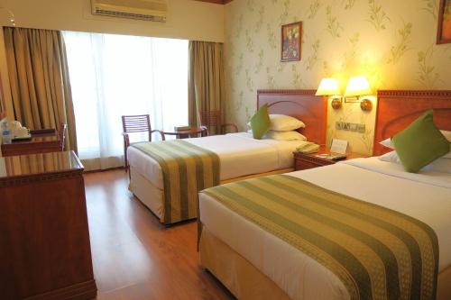 a hotel room with two beds and a window at Riviera Hotel in Dubai