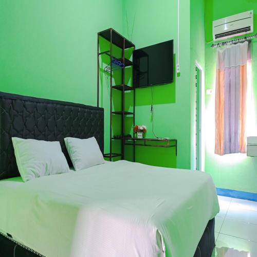 Un dormitorio con una cama blanca y una pared verde. en Hotel Pabelan RedPartner, en Bengkulu