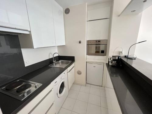 une cuisine avec des armoires blanches, un évier et un lave-vaisselle dans l'établissement 204 - Cannes La Croisette - Studio face mer avec balcon, à Cannes