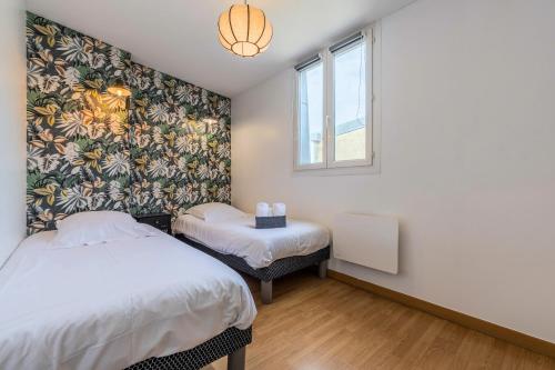 una camera da letto con due letti e una finestra di Le Cottage du Louvre a Lens