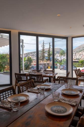 a dining room with a table with chairs and windows at Grand Hotel Saranda in Sarandë