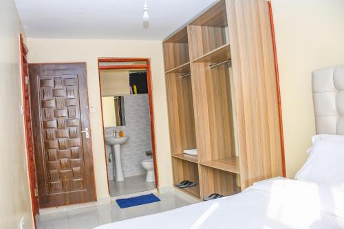a bedroom with a bed and a door and a bathroom at Ligen Suites in Kakamega