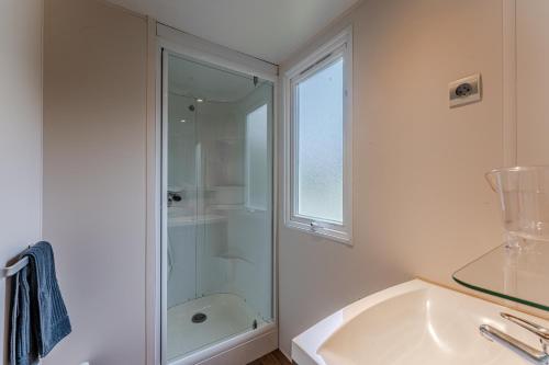 a white bathroom with a shower and a sink at Mobil Home Confort Avec Clim 6 in Onesse-et-Laharie