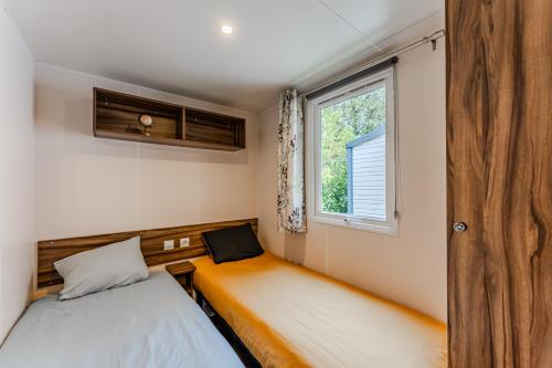 a small bedroom with two beds and a window at Mobil Home Confort Avec Clim 6 in Onesse-et-Laharie