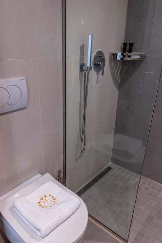 a bathroom with a shower and a toilet with a towel at Grand Hotel Saranda in Sarandë