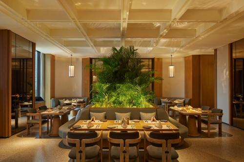 a restaurant with tables and chairs and a large plant at Hotel Tentrem Jakarta in Serpong