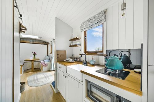 a kitchen with white cabinets and a sink and a window at Fferm Fach By Birch Stays in Llandegfan