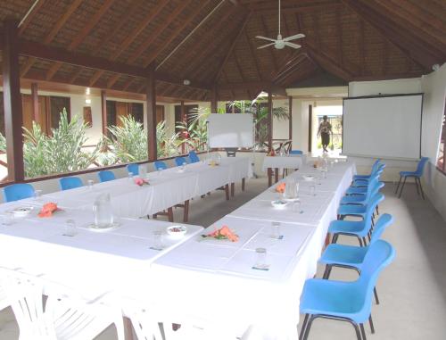 a large conference room with white tables and blue chairs at Beachfront Resort in Luganville