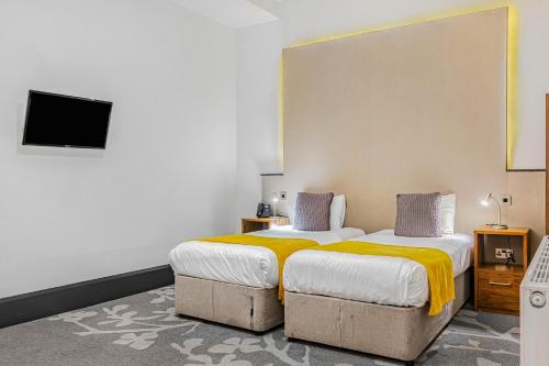 a bedroom with two beds and a flat screen tv at The Ainscow Hotel in Manchester