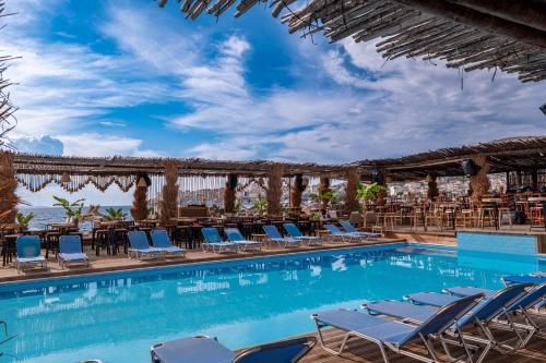 a swimming pool with lounge chairs and tables and the ocean at Grand Hotel Saranda in Sarandë