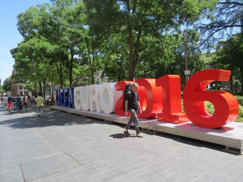 a person walking past a large sign that says plus at Hotel Ours Blanc - Victor Hugo in Toulouse