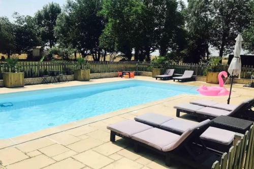 - une piscine avec des chaises longues et un flamingo rose dans l'établissement Demeure spacieuse avec piscine dans le Perche, à La Veronnière