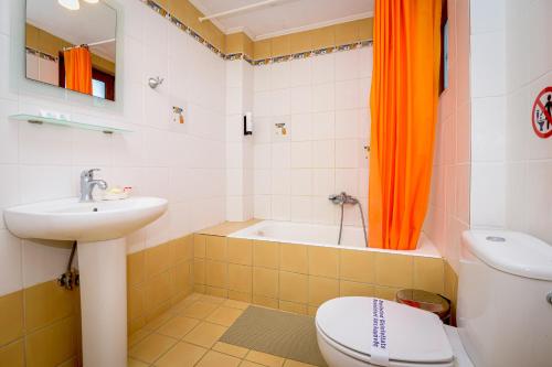 a bathroom with an orange curtain and a toilet and a sink at Thea Dikella in Dhíkella