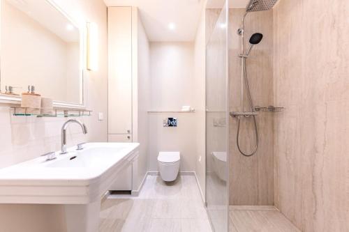 une salle de bain blanche avec un lavabo et une douche dans l'établissement Arc de Triomphe Luxury 3 Bed 3,5 Bath, à Paris