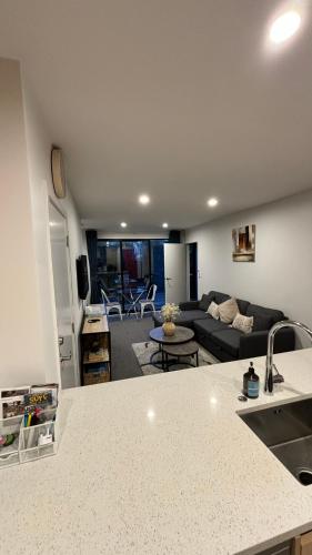 a kitchen and a living room with a couch at Close to City and Beach - Modern Home with Garage in Christchurch