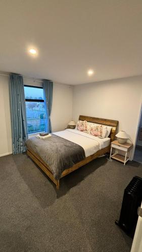 a bedroom with a large bed and a window at Close to City and Beach - Modern Home with Garage in Christchurch