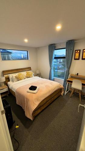a bedroom with a large bed with a desk and two windows at Close to City and Beach - Modern Home with Garage in Christchurch