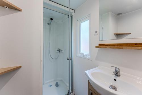 une salle de bain blanche avec une douche et un lavabo dans l'établissement Bungalow 2 Chambres Avec Clim, à Saint-Julien-en-Born