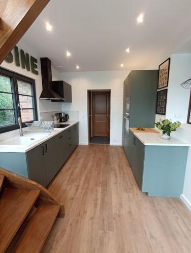 Il comprend une grande cuisine avec des comptoirs blancs et du parquet. dans l'établissement Côté Marais Amiens, à Camon