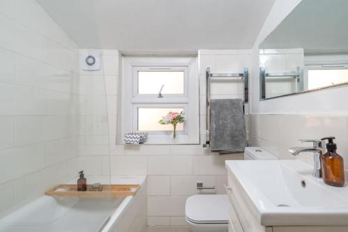 a white bathroom with a sink and a toilet at New 4BD Stylish Apartment with Amazing Transport in London