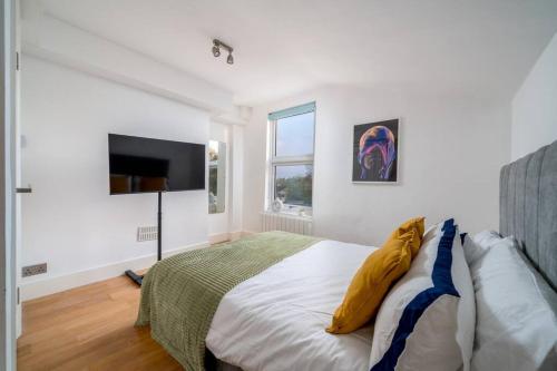 a white bedroom with a bed and a flat screen tv at New 4BD Stylish Apartment with Amazing Transport in London