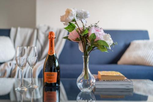 a bottle of wine and a vase with flowers on a table at New 4BD Stylish Apartment with Amazing Transport in London