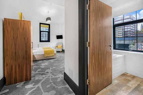 a bedroom with a bed and a bathroom with a tub at The Ainscow Hotel in Manchester
