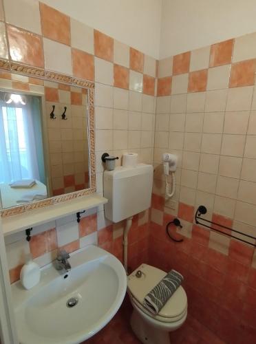 a bathroom with a sink and a toilet and a mirror at Villa Anita Rooms in Gatteo a Mare