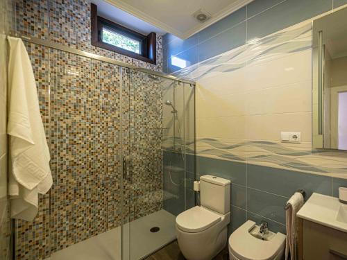 a bathroom with a toilet and a glass shower at Lujo a estrenar con piscina cubierta in Teo