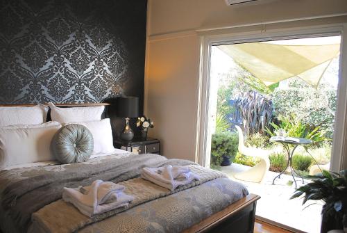 a bedroom with a bed and a large window at Bed of Roses in Apollo Bay
